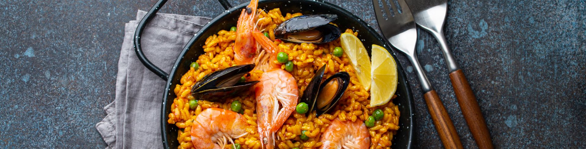 Seafood paella, a classic dish of Spain, in the traditional dish on a rustic table.