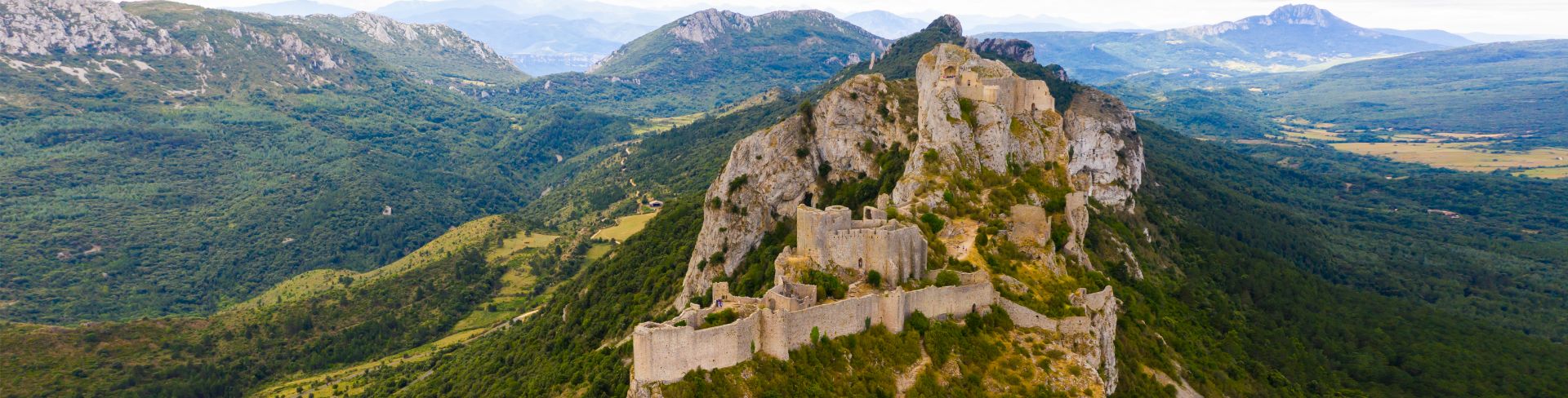 An aerial view of the ruins of Cathar castle of Peyrepertuse perched on a rocky ridge.