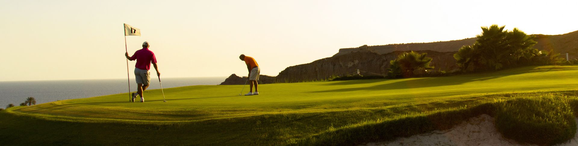 A pair of golfers playing on the putting green.