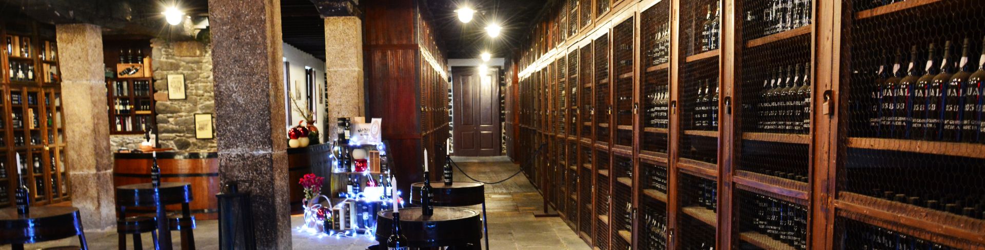 A wine cellar lined with bottles of wine and tasting tables in the center.