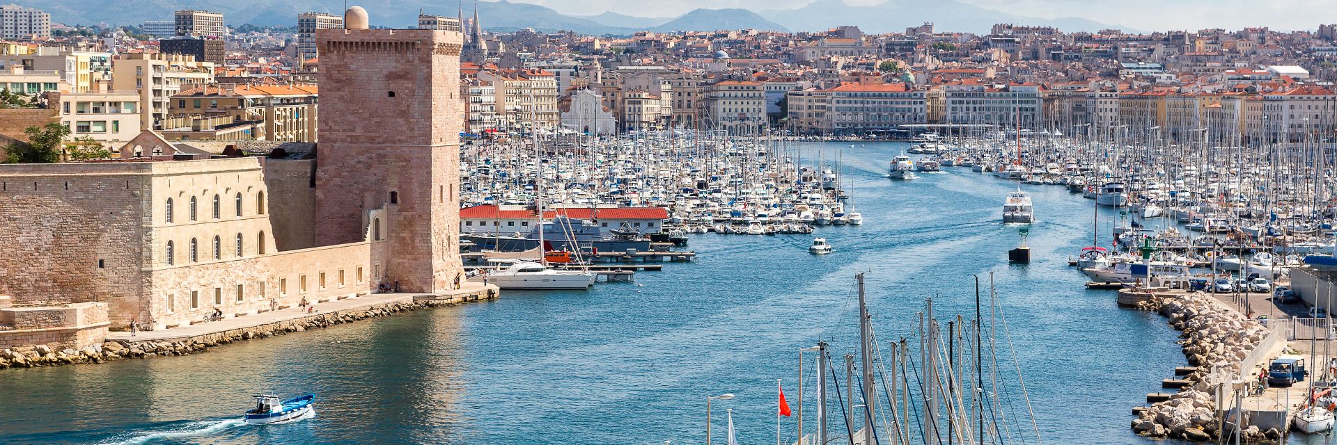 Clouds in a bright blue sky overlooking a colorful skyline and blue water.