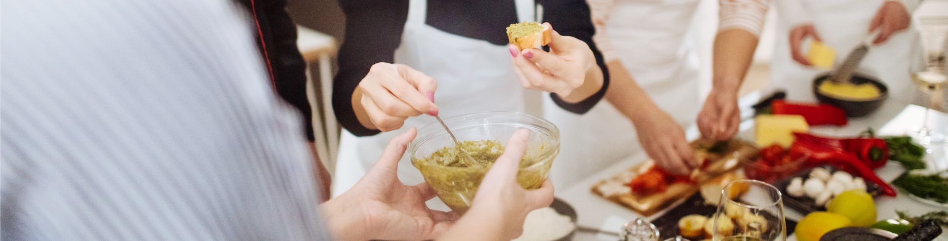 Four people joyfully gather around a table filled with ingredients as they learn a new recipe 