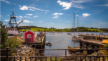 Blue sky over a port with small red house and boats.