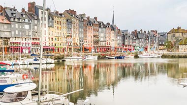 Pastel colored old homes line the water where fishing boats are docked.