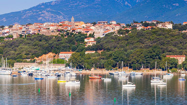 Orange roofs nestled into the coastline above the water.