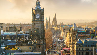 An old clocktower towers over the rest of the city at dusk.