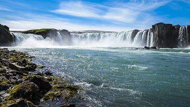 A large waterfall cascading down into blue water.