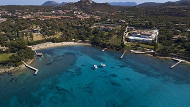 A view from above, of the coast showing blue water, white sandy beaches and green land.