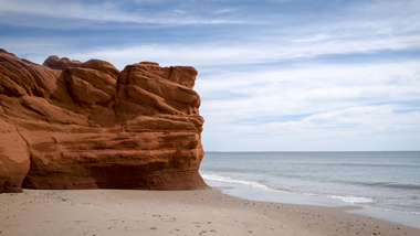 Large warm orange-hued cliff overlooking the beach and ocean.
