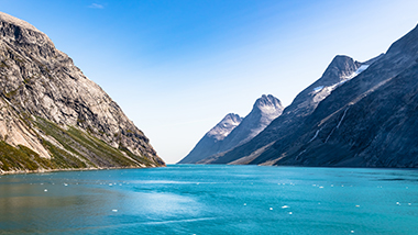Bright blue water meets two converging mountains on either side.