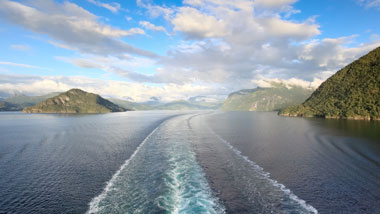 The wake of a ship with islands in the background.