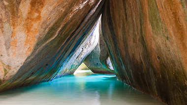 Large rocks form a triangle pathway through shallow, vibrant blue water.