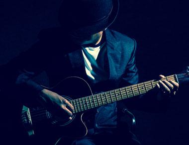 A man in the dark playing a guitar.
