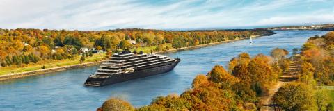 The Ritz-Carlton Yacht Collection crossing a river surrounded by tundra nature.