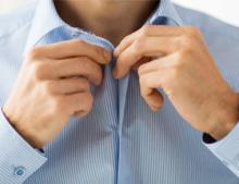 A man buttoning his blue shirt.