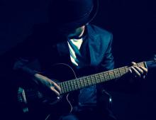 A man in the dark playing a guitar.