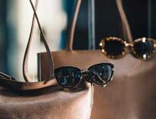 Two brown purses with sunglasses displayed in a store window.