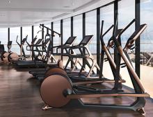 A rendering of the gym, showing a row of exercise equipment overlooking a view of the sea from a high deck