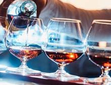 Three glasses being filled with liquor.