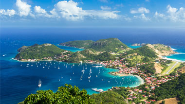 An aerial view of an island stretching out into deep blue water.